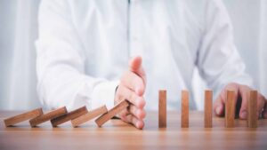 Businessman hand stop falling down of wood block .planing and strategy business disruption concept.